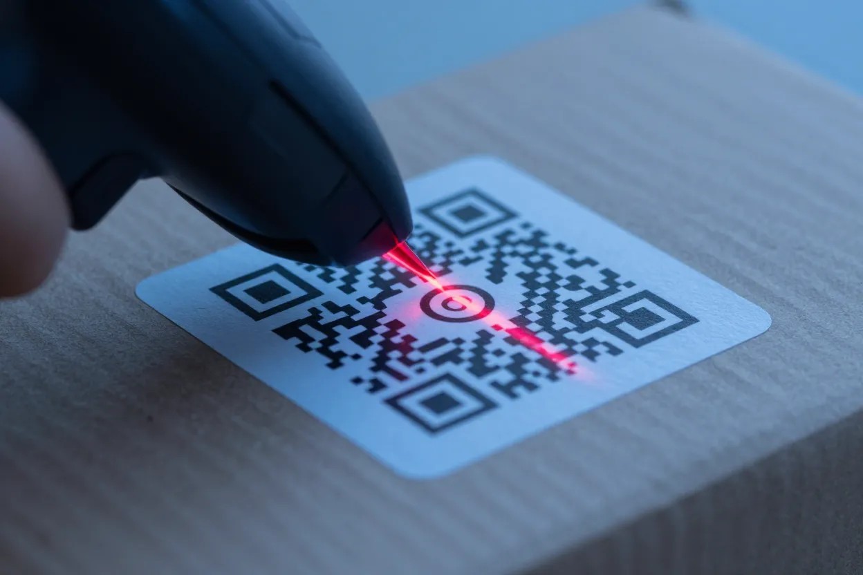 Φορητός σαρωτής διαβάζει κωδικό QR σε κιβώτιο με κόκκινη δέσμη